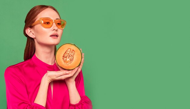 Beautiful redhead woman holding a melon with copy space