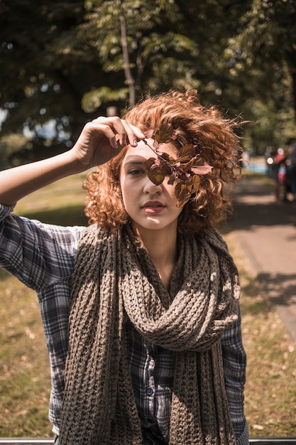 Foto gratuita bella donna della testarossa in foglie della holding della sciarpa