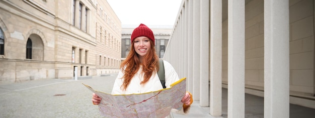 無料写真 市内地図を持つ美しい赤毛の女性観光客は、ウォーキング観光歴史的建造物を探索します