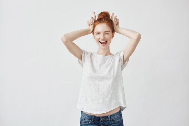 Beautiful redhead woman winking smiling showing hare hands.