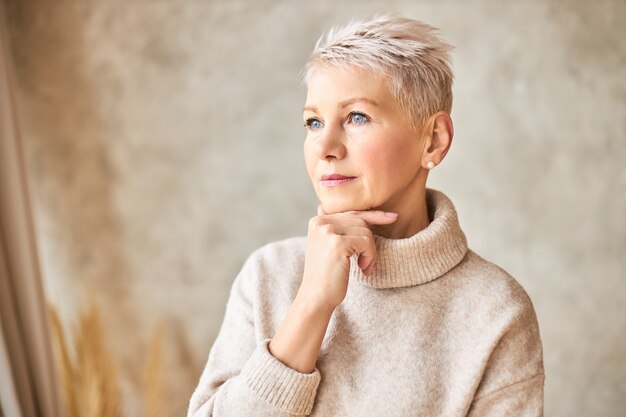 Beautiful retired woman wearing cozy sweater and short hairdo