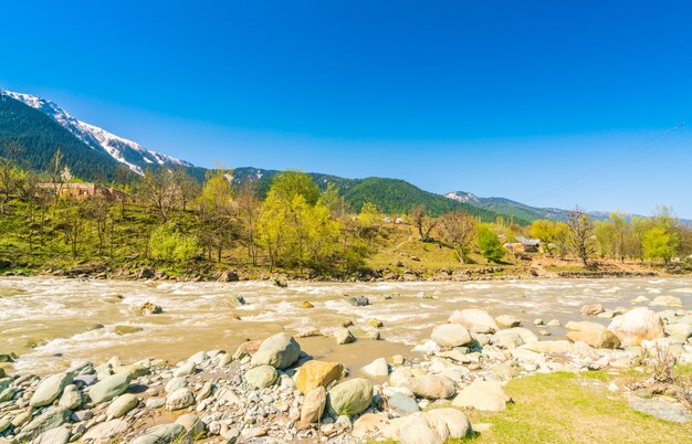 カシミール州、インドの美しい川と雪の山々の景観。