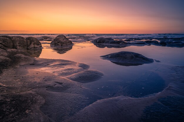 日没時のオーストラリア、クイーンズランド州の美しい岩の多い海岸