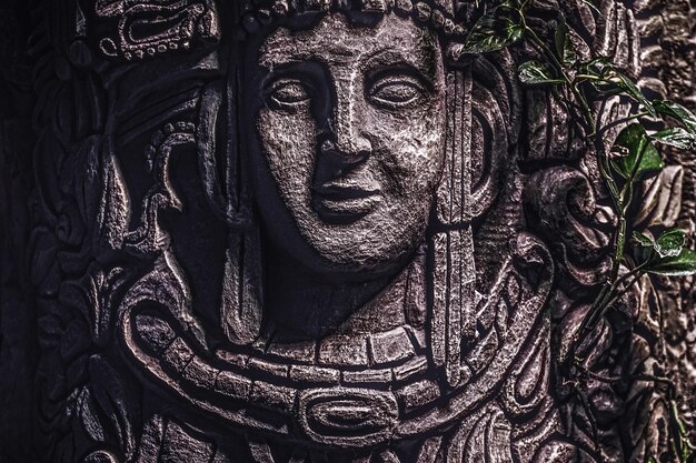 Beautiful rocky monument with a carved image of a human face in the jungle. Close-up view