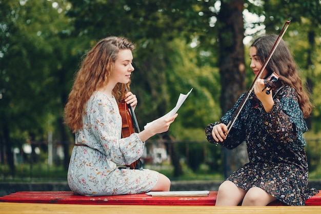 Красивые и романтичные девушки в парке со скрипкой