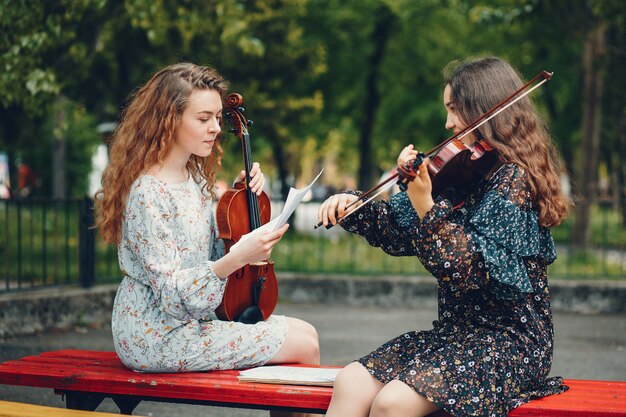 Красивые и романтичные девушки в парке со скрипкой