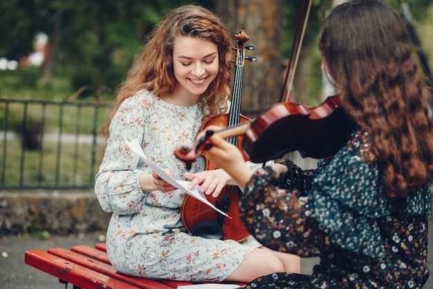 Free photo beautiful and romantic girls in a park with a violin