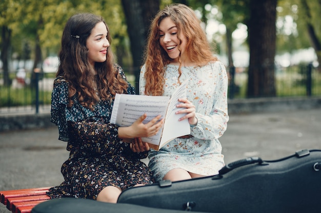 Free photo beautiful and romantic girls in a park with a violin