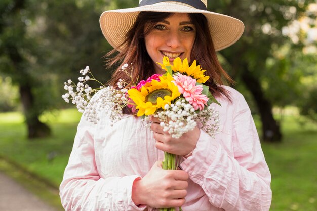 Beautiful romantic woman in hat holding flowers 