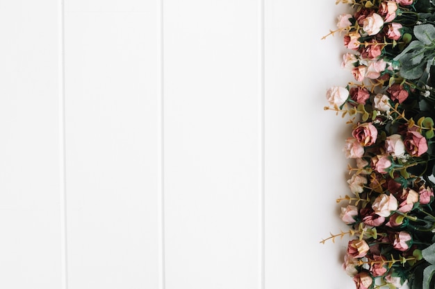 Free photo beautiful roses over great white wooden background with space on the right