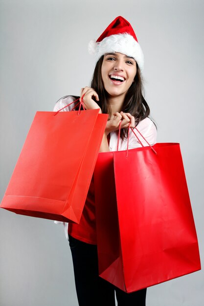 Beautiful santa girl  carrying red shopping bags