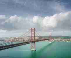 Free photo beautiful scenery of the 25 de abril bridge in portugal under the breathtaking cloud formations