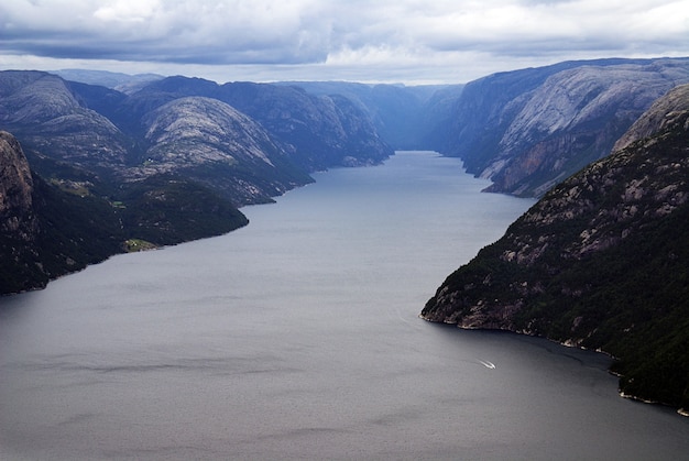 Beautiful scenery of famous Preikestolen cliffs near a lake under a cloudy sky in Stavanger, Norway