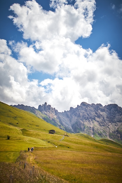 Красивые пейзажи зеленого пейзажа с высокими скалистыми утесами под белыми облаками в Италии