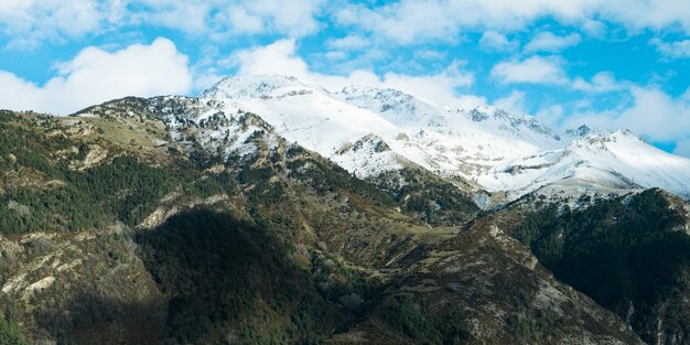 Красивые пейзажи высокого скалистого горного хребта, покрытого снегом, под пасмурным небом