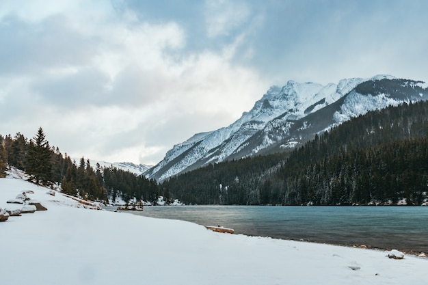 Beautiful scenery of a lake surrounded by high rocky mountains covered with snow under the sunlight