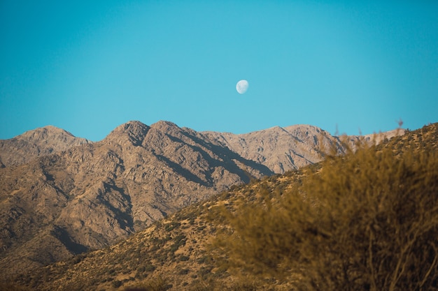 Beautiful scenery of a mountain range at sunset and the moon out