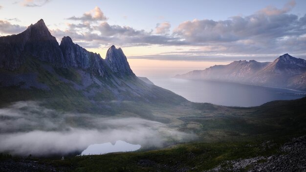 夕焼けの息を呑むような曇り空の下、海沿いの岩の崖の美しい風景