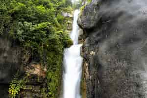 Foto gratuita bellissimo scenario di una cascata che scorre attraverso scogliere rocciose