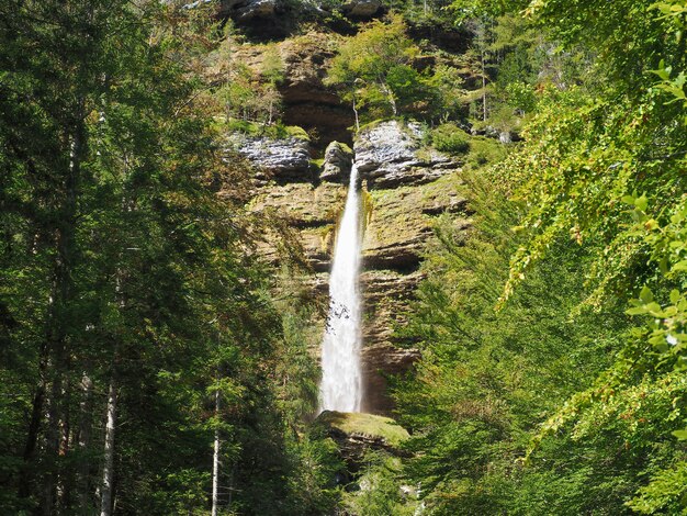 Beautiful scenery of the waterfall that goes through the rocks covered in moss in the forest