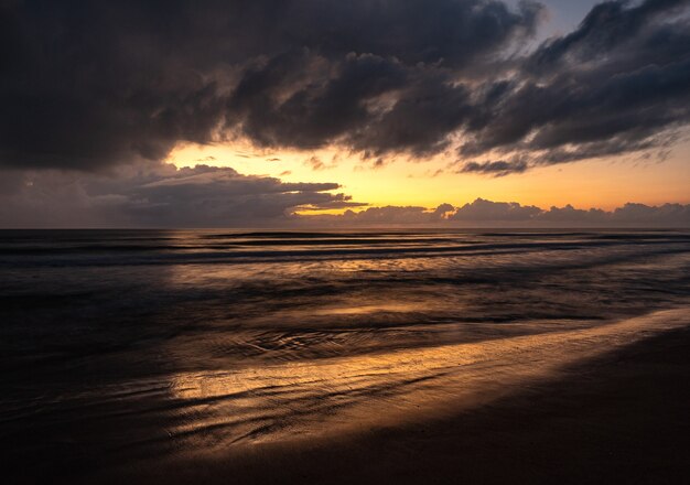 Beautiful scenery of a wavy sea under a cloudy sky at sunrise