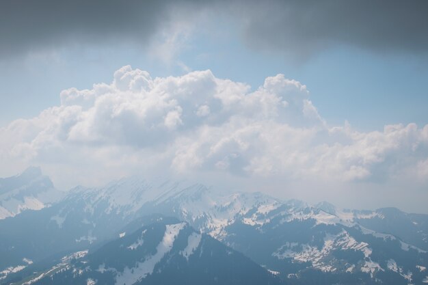Красивые пейзажи белых облаков, покрывающих хребет высоких скалистых гор.