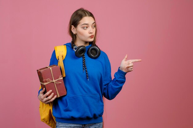 Beautiful schoolgirl standing looking aside pointing by finger