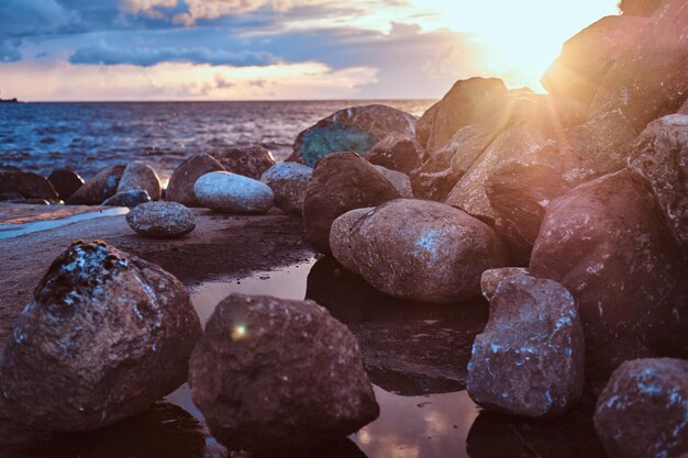 素晴らしい明るい夕日を背景に、石のある美しい海辺。