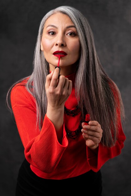 립스틱을 적용하는 아름 다운 수석 여자 초상화
