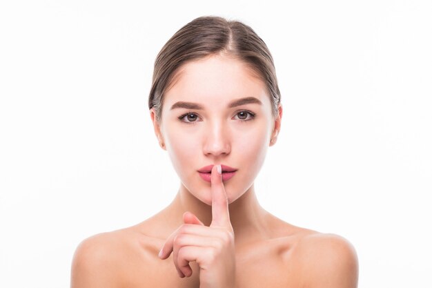 Beautiful sensual woman saying shh with finger on lips isolated on white wall