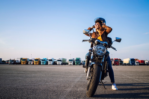 Free photo beautiful sexy brunette woman in leather jacket sitting on retro style motorcycle getting ready for the ride.