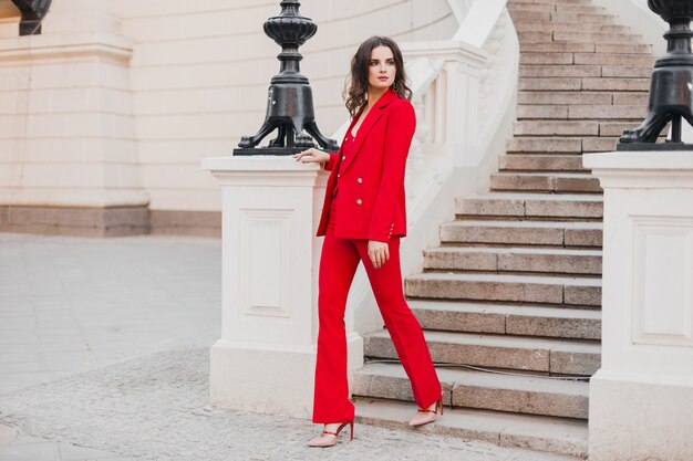 Beautiful sexy rich business style woman in red suit walking in city street, spring summer fashion trend