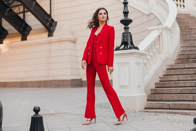 Beautiful sexy rich business style woman in red suit walking in city street, spring summer fashion trend