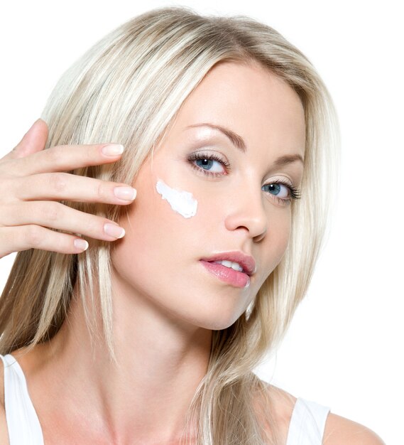 Beautiful sexy woman applying cosmetic cream on face - isolated