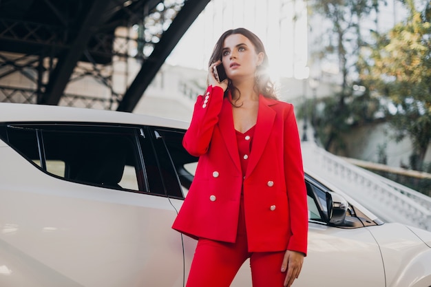전화 사업에 얘기하는 차에서 포즈를 취하는 빨간 옷에 아름 다운 섹시 한 여자