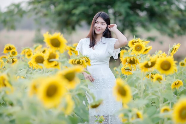 beautiful sexy woman in a white dress walking on a field of sunflowers