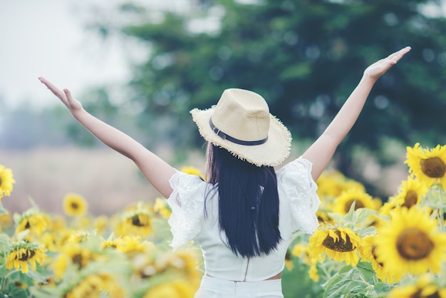 Free photo beautiful sexy woman in a white dress walking on a field of sunflowers