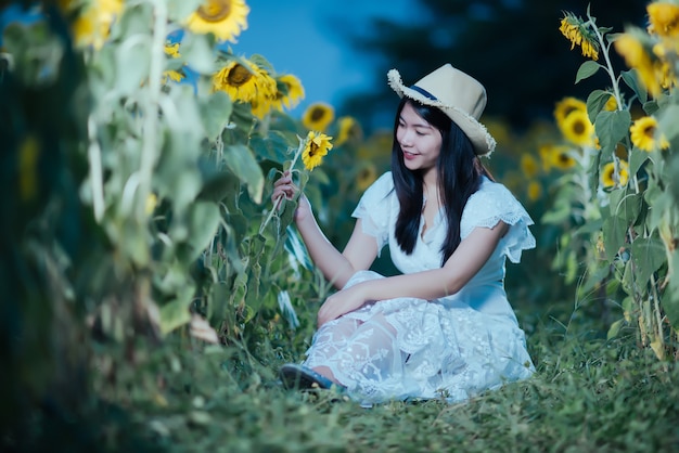 beautiful sexy woman in a white dress walking on a field of sunflowers