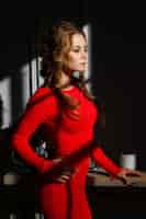 Foto gratuita bella giovane donna sexy in un abito rosso su uno sfondo grigio