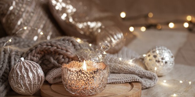 Beautiful shiny silver christmas decor and burning candle close up. Cozy winter atmosphere.