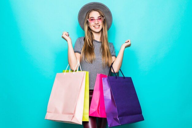 Beautiful shopping woman smiling and wearing a hat isolated over green background