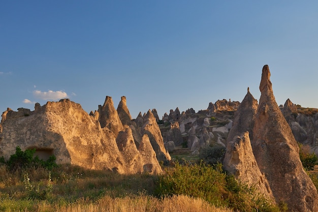 Bella ripresa di grandi rocce su una collina erbosa sotto un cielo blu chiaro