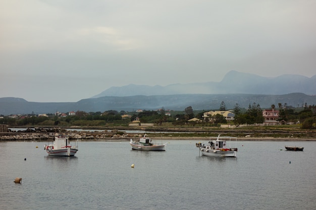 Foto gratuita bellissimo scatto di barche sull'acqua con edifici e montagne in lontananza