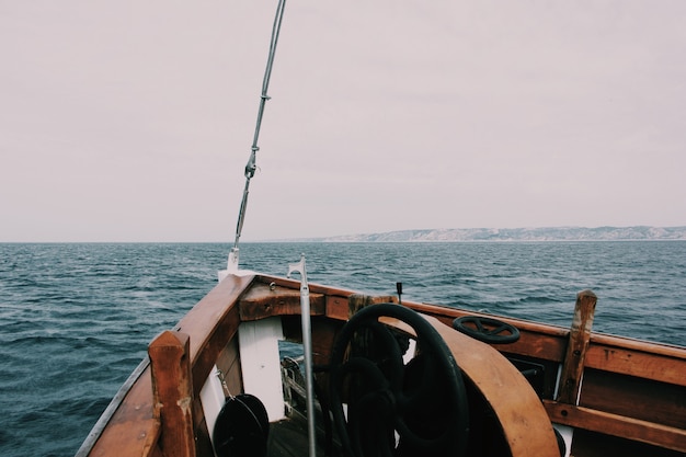 Foto gratuita bello colpo di una prua della barca sul mare con le colline e un nuvoloso nei precedenti