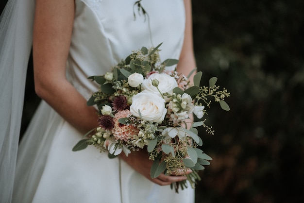 Beautiful shot of a bride wearing wedding dress holding a flower bouquet