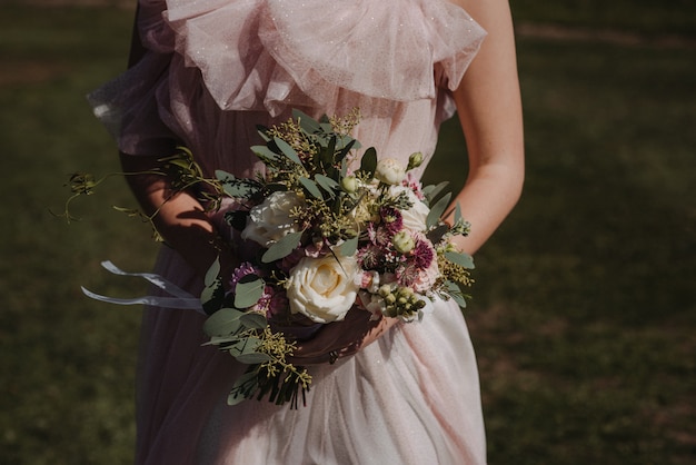 花束を持ってウェディングドレスを着ている花嫁の美しいショット