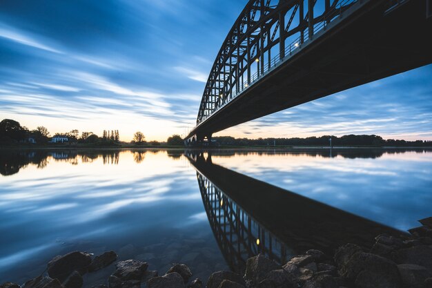 Красивый снимок моста через озеро с отражающими лучами во время заката