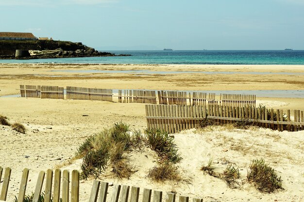 砂の上の木製のフェンスでいっぱいの海岸の美しいショット