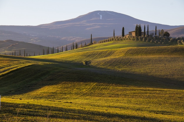 Beautiful shot of a country house in the middle of a field surrounded by hills under the clear sky