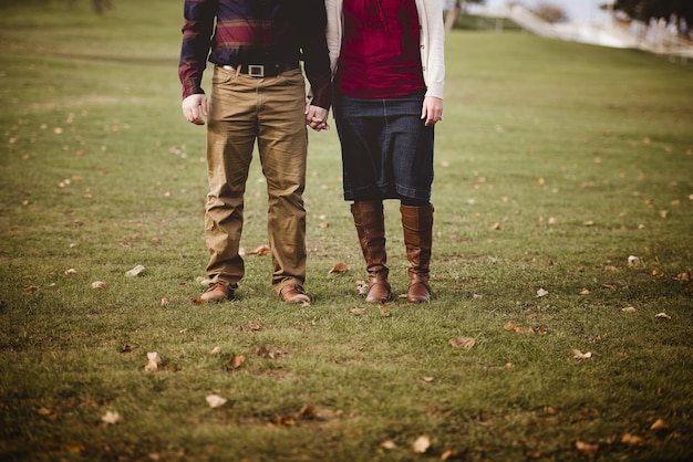 Beautiful shot of a couple holding hands while standing in a grassy field with a blurred background